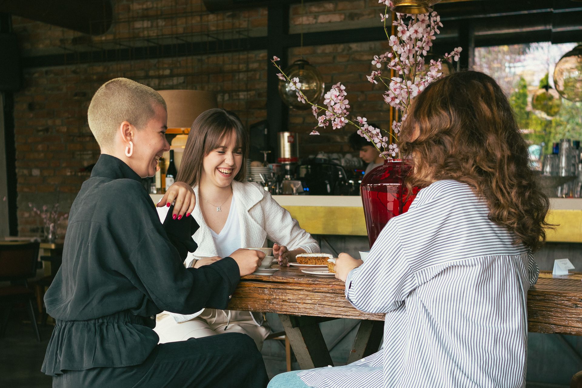 Friends laughing over cake and coffee in a café