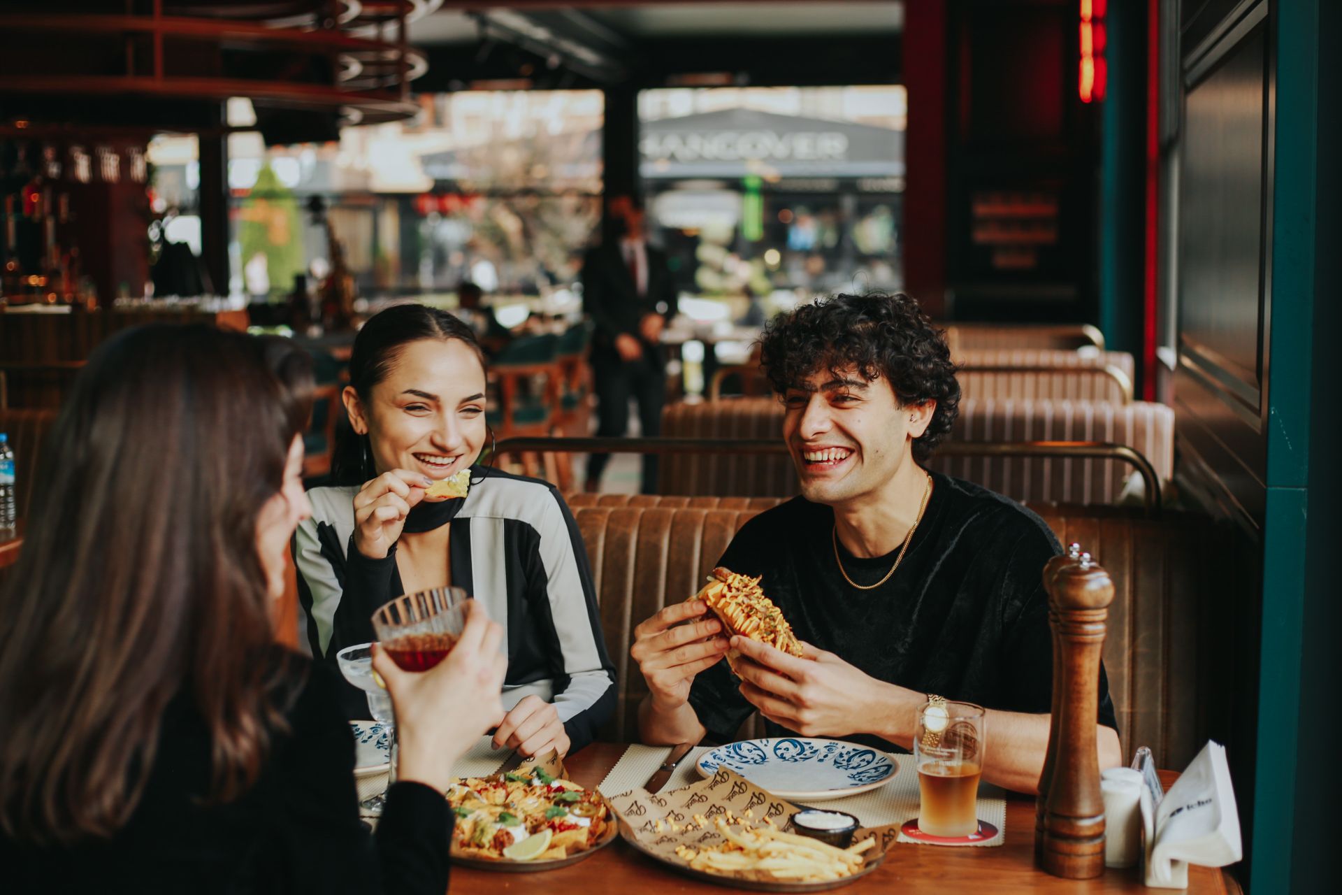 A group of friends laughing together over drinks and food