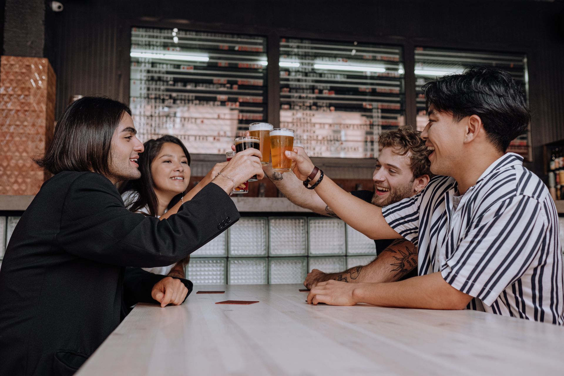 Friends laughing and clinking glasses in a busy pub