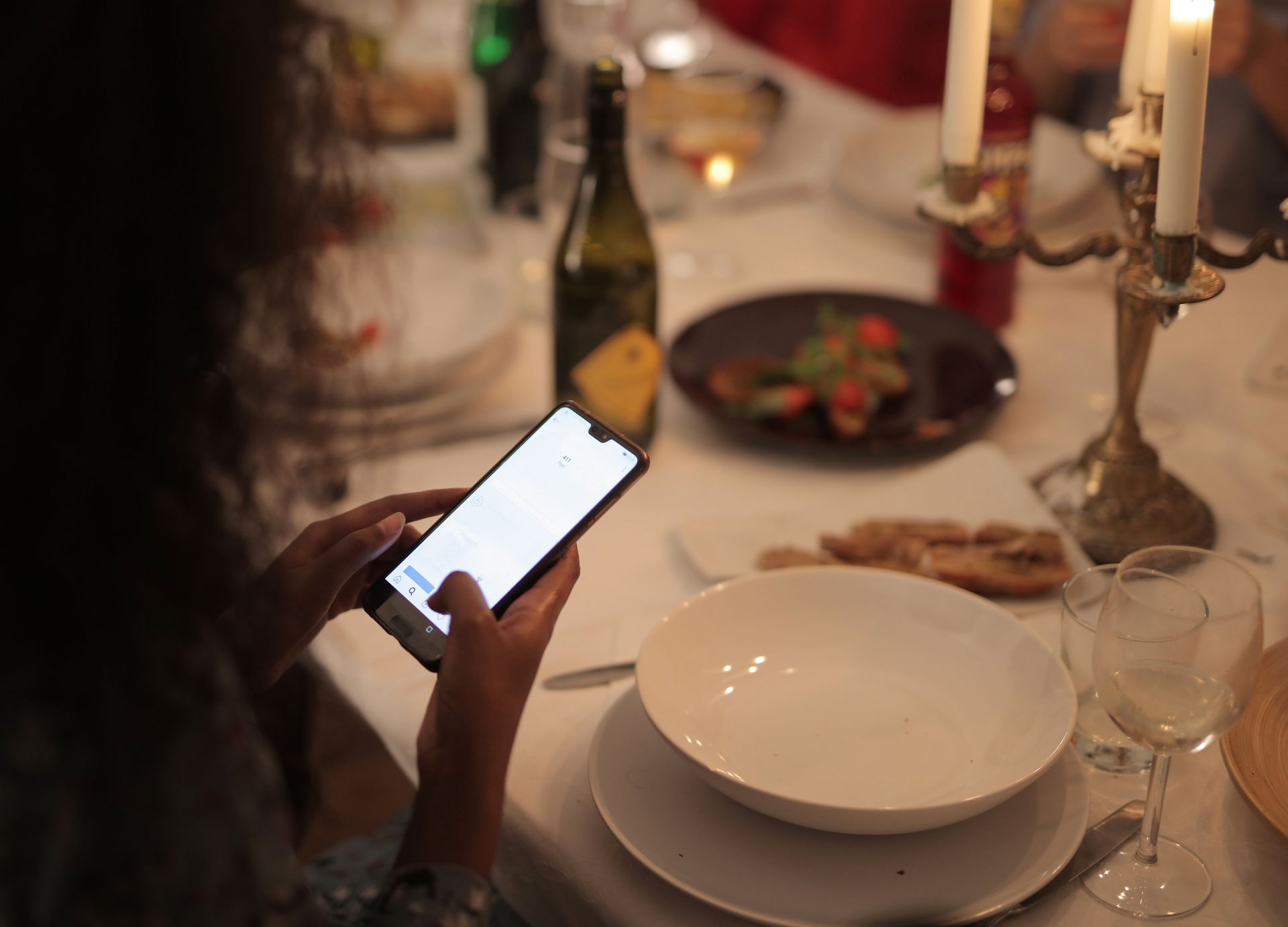 Customer ordering from their phone at a candlelit restaurant table
