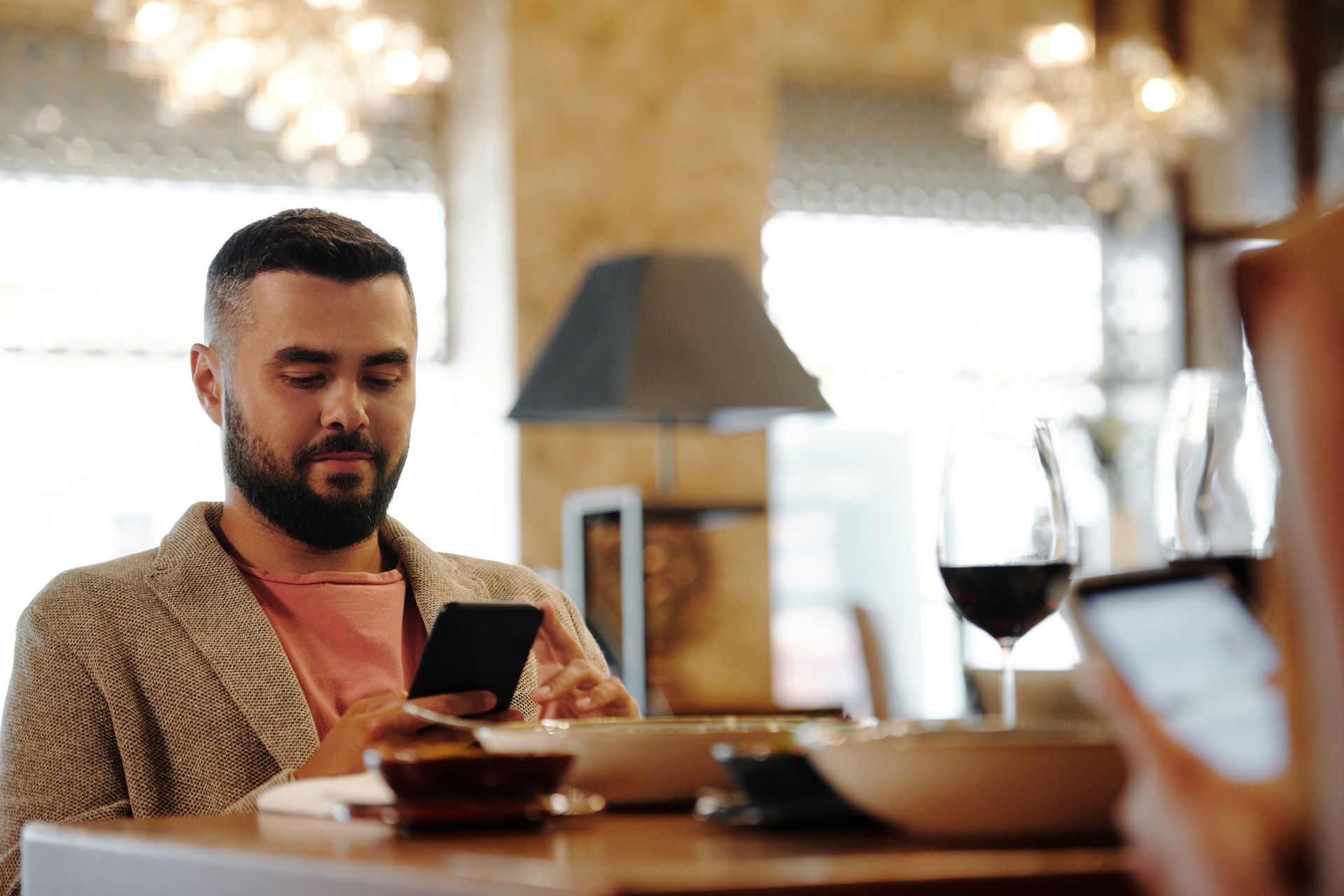 Customer browsing the menu on their phone over a glass of wine